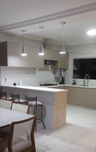 Cozinha planejada Canaã com balcão em mármore, pendentes e banquetas